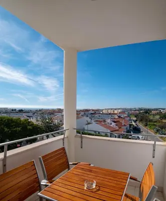 a balcony with a wooden table and chairs at Vila Petra in Albufeira