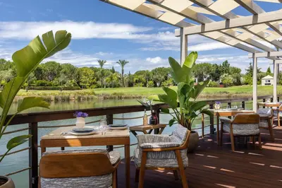 a patio with tables and chairs next to a body of water at Domes Lake Algarve, Autograph Collection in Vilamoura