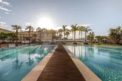 a swimming pool at a resort with palm trees at Domes Lake Algarve, Autograph Collection in Vilamoura