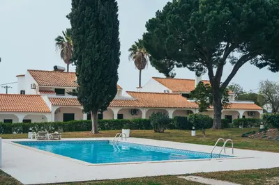 a swimming pool in front of a house with trees at Apartamentos Vale de Carros by Umbral in Albufeira