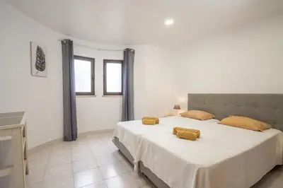 a white bedroom with two beds and two windows at Apartamentos Vale de Carros by Umbral in Albufeira