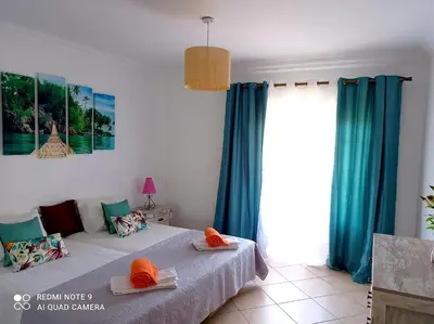 a bedroom with blue curtains and a bed with hats on it at Seashell Apartment OURA in Albufeira