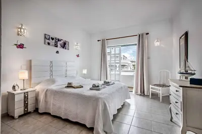 a white bedroom with a bed and a window at Villa Torcato in Albufeira