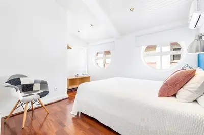 a bedroom with a white bed and a chair at RG Downtown Duplex in Faro