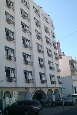a large white building with cars parked in front of it at Hotel Alnacir in Faro