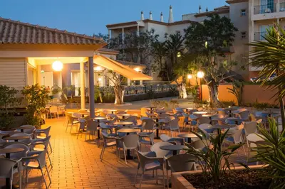 an outdoor patio with tables and chairs at night at 3HB Clube Humbria - All Inclusive in Albufeira