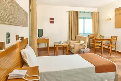 a hotel room with a bed and a living room at Oceanus Aparthotel in Albufeira