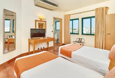 a hotel room with two beds and a desk at Oceanus Aparthotel in Albufeira