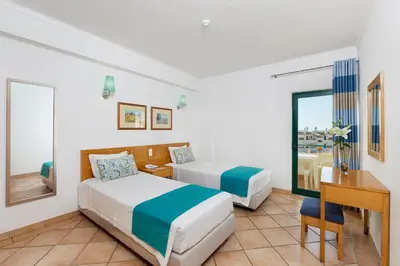 a hotel room with two beds and a desk at Oceanus Aparthotel in Albufeira