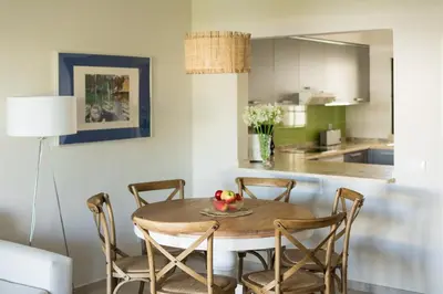 a dining room table with chairs and a kitchen at Clube Albufeira Garden Village in Albufeira