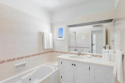 a white bathroom with a tub and a sink at Clube Albufeira Garden Village in Albufeira