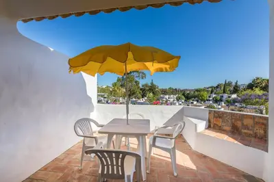 a table and chairs with a yellow umbrella on a balcony at 60m2 Lovely traditional apartment in Clube Albufeira in Albufeira