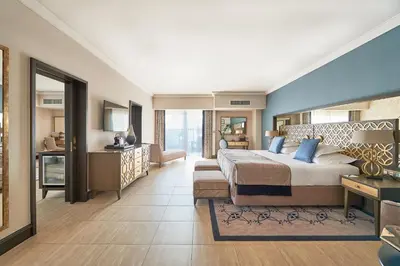 a bedroom with a large bed and a living room at Dona Filipa Hotel in Vale do Lobo
