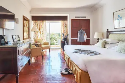 a bedroom with a large bed with a dresser and a room at Dona Filipa Hotel in Vale do Lobo