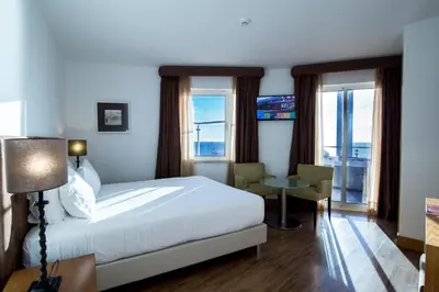 a hotel room with a bed and a desk and windows at Hotel Quarteirasol in Quarteira