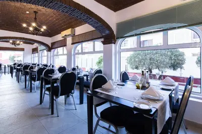 a large swimming pool in a hotel with tables and chairs at Hotel Quarteirasol in Quarteira