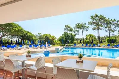 a patio with tables and chairs next to a swimming pool at Victory Village 2A in Quinta do Lago