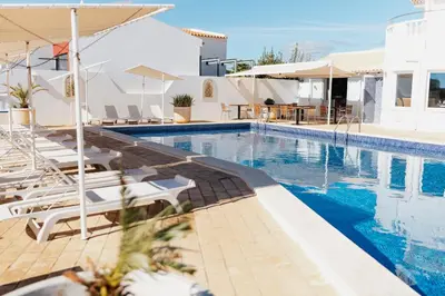 a swimming pool with chairs and umbrellas at a hotel at Vila Channa - Adults Only in Albufeira