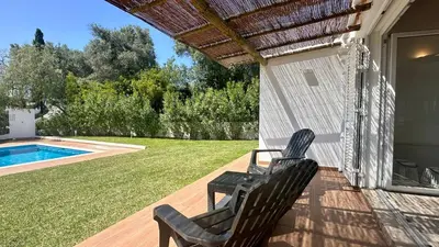 two chairs sitting on a porch next to a swimming pool at Galo by Check-in Portugal in Albufeira