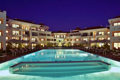 a large swimming pool in front of buildings at night at As Cascatas Golf Resort & Spa in Vilamoura