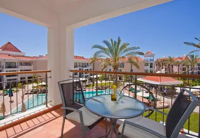 a balcony with a table and chairs and a view of the pool at As Cascatas Golf Resort & Spa in Vilamoura