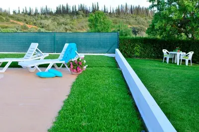 a patio with two chairs and a table in the grass at Quinta das Amendoeiras in Albufeira