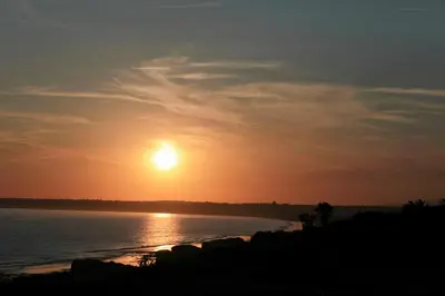 a sunset over the water with the sun in the sky at Quinta das Amendoeiras in Albufeira