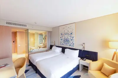 a hotel room with two beds and a desk at Hilton Vilamoura in Vilamoura