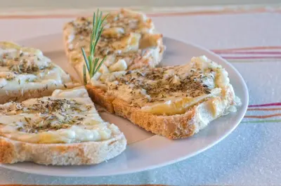 a plate with slices of bread with cheese and herbs at Quinta Do Mel in Albufeira