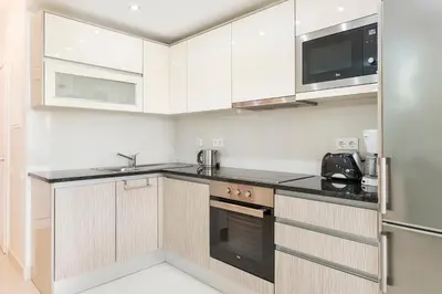 a kitchen with white cabinets and black counter tops at Victory Village Club 9F in Quinta do Lago