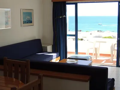 a living room with a couch and a view of the beach at Almar Hotel Apartamento in Albufeira