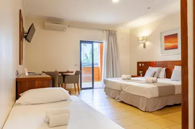 a hotel room with two beds and a table and a desk at Hotel Praia Sol in Quarteira
