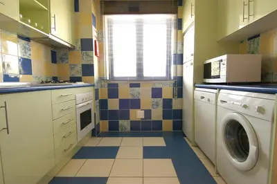 a small kitchen with a washer and dryer at Orada Apartamentos Turísticos - Marina de Albufeira in Albufeira