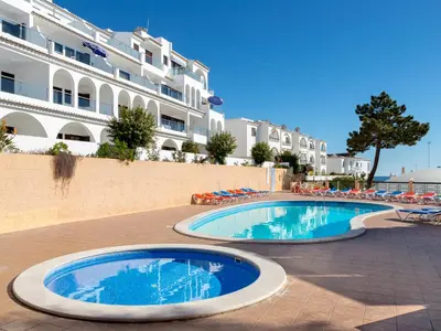 two swimming pools in front of a large building at Apartamentos Do Parque in Albufeira