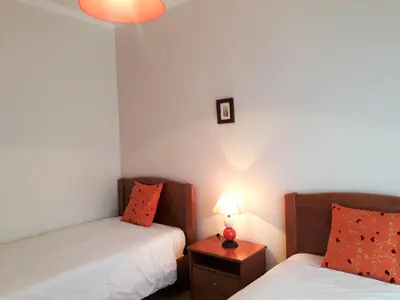 a bedroom with two beds and a lamp on a night stand at T2 Tahíti - Terraço, Familiar, Garagem, Wifi in Quarteira