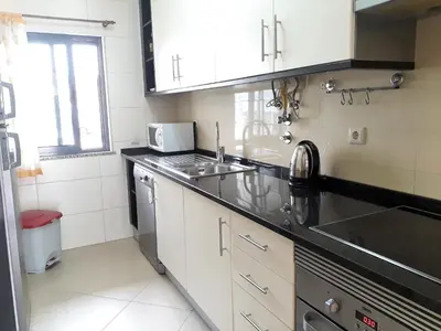 a small kitchen with a sink and a stove at T2 Tahíti - Terraço, Familiar, Garagem, Wifi in Quarteira
