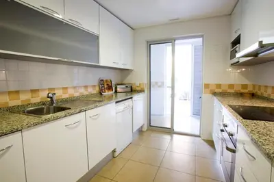 a kitchen with white cabinets and a sink and a window at Varandas de Carteia G/F in Quarteira