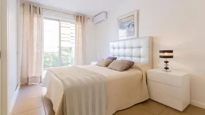 a white bedroom with a bed with a window at Varandas de Carteia G/F in Quarteira