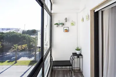 a balcony with a chair and a large window at Apartamento Gulbenkian in Faro