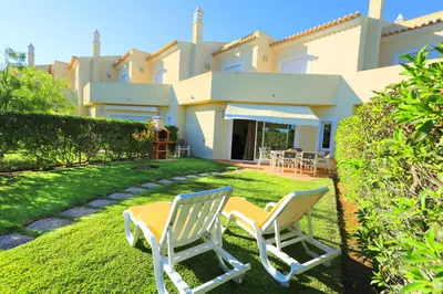 two chairs sitting on the lawn in front of a house at Balaia Harmonia in Albufeira