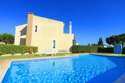 a villa with a swimming pool in front of a house at Balaia Harmonia in Albufeira