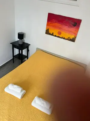 a bedroom with a yellow bed with a painting on the wall at Casinha in Faro