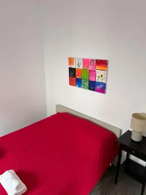 a bedroom with a red bed and a painting on the wall at Casinha in Faro