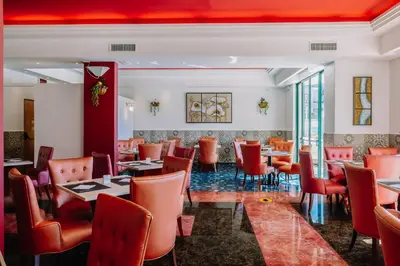 a restaurant with red chairs and tables and a bar at Grand Muthu Forte Da Oura in Albufeira