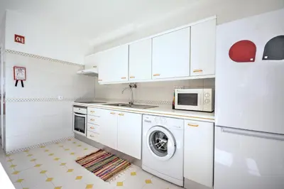 a kitchen with a washing machine and a microwave at In Faro with Sea View in Faro