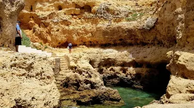 a person standing in a canyon with a body of water at Albufeira Ocean Terrace (31) in Albufeira