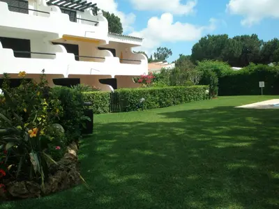 a yard in front of a house with green grass at Apartamento Solar dos Pinheiros in Vilamoura