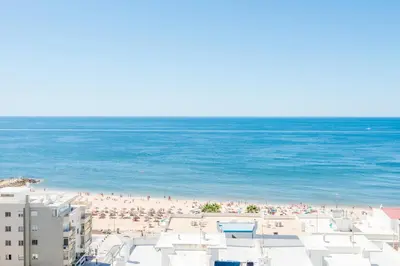 a beach with a lot of people and the ocean at Vista Mar in Quarteira