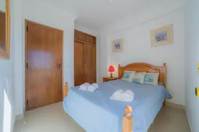 a bedroom with a bed and a cabinet and a mirror at Atlantida by Garvetur in Quarteira