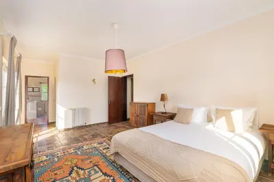 a bedroom with a large white bed and a table at Quinta das Figueiras - Bordeira - Faro in Bordeira